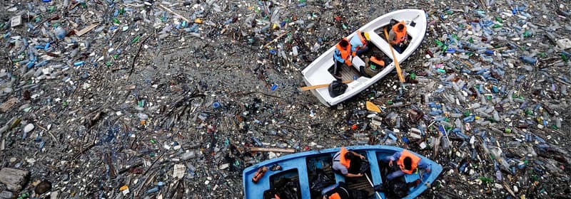 Boat floating in an ocean full of litter