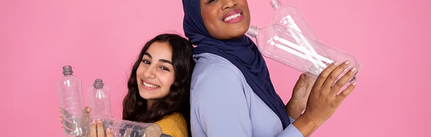 A girl wearing hijab and an indian girl holding PET bottles