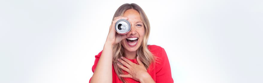 Smiling woman holding a can up to her eye
