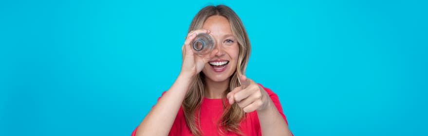 Blondes Mädchen vor rosafarbenem Hintergrund, das auf etwas zeigt