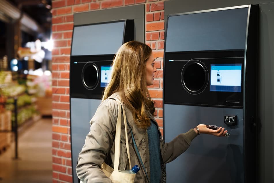 Woman getting money back on mobile from reverse vending machine