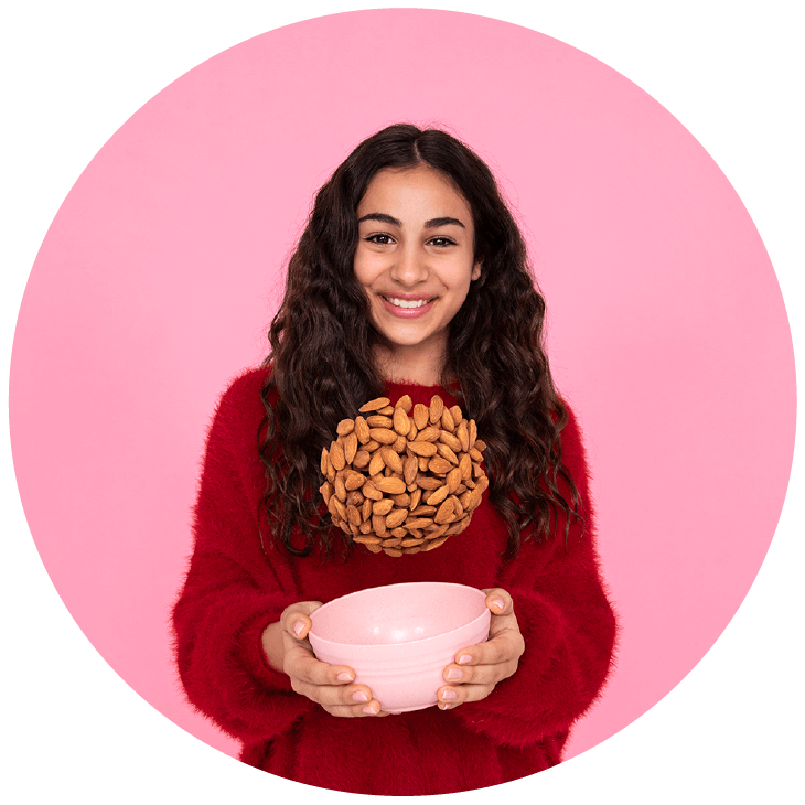 Femme tenant un bol duquel proviennent des amandes lancées en l'air