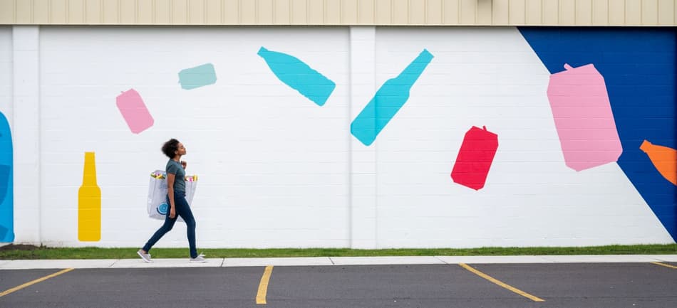 Image of person heading to recycling containers
