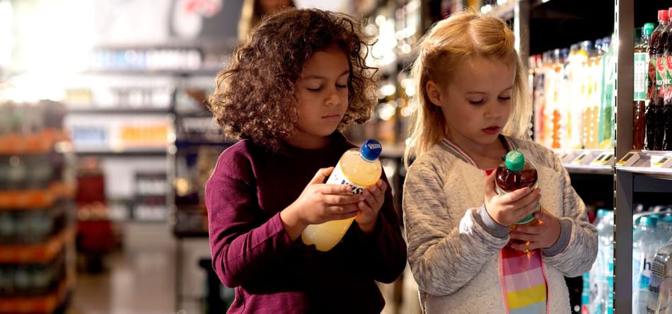 Girls looking at container labels in supermarket