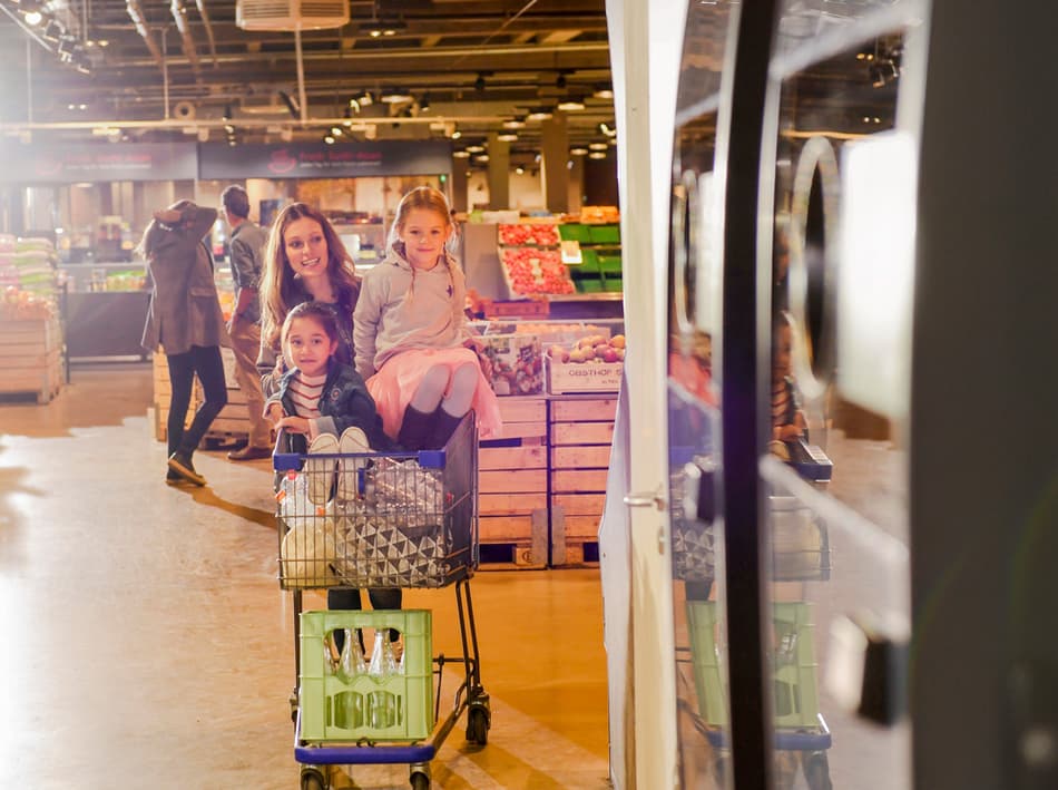 Family with trolley containing containers approaching reverse vending machine