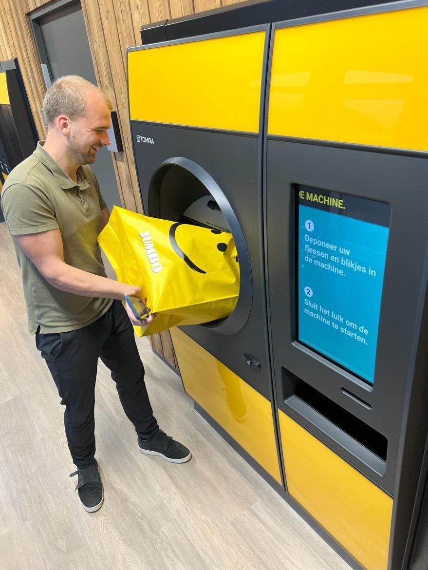 A man pouring a bag of containers into a TOMRA R1 reverse vending machine