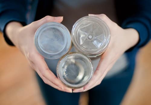 two hands holding three empty plastic bottles