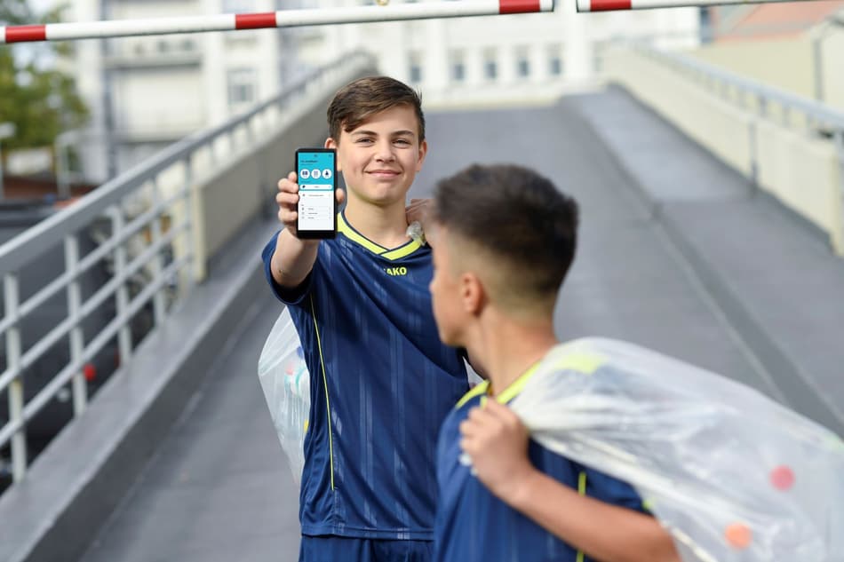 Image of boys with myTOMRA app and bags of containers for recycling