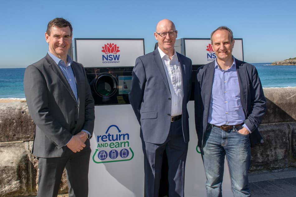image of three men standing with a reverse vending machine