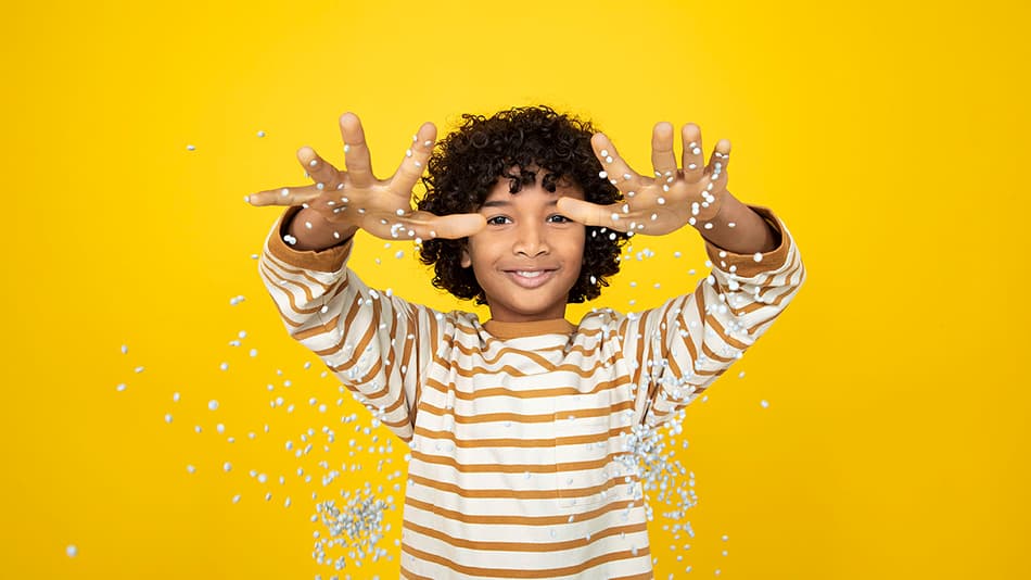 Niño soltando granza de plástico con las manos abiertas