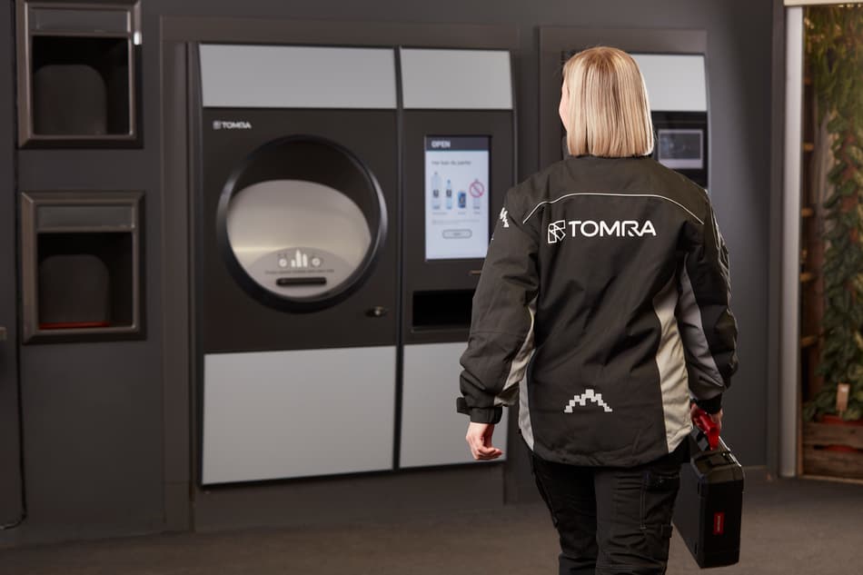 TOMRA service-ansatt dame som går til TOMRA R1 panteautomat